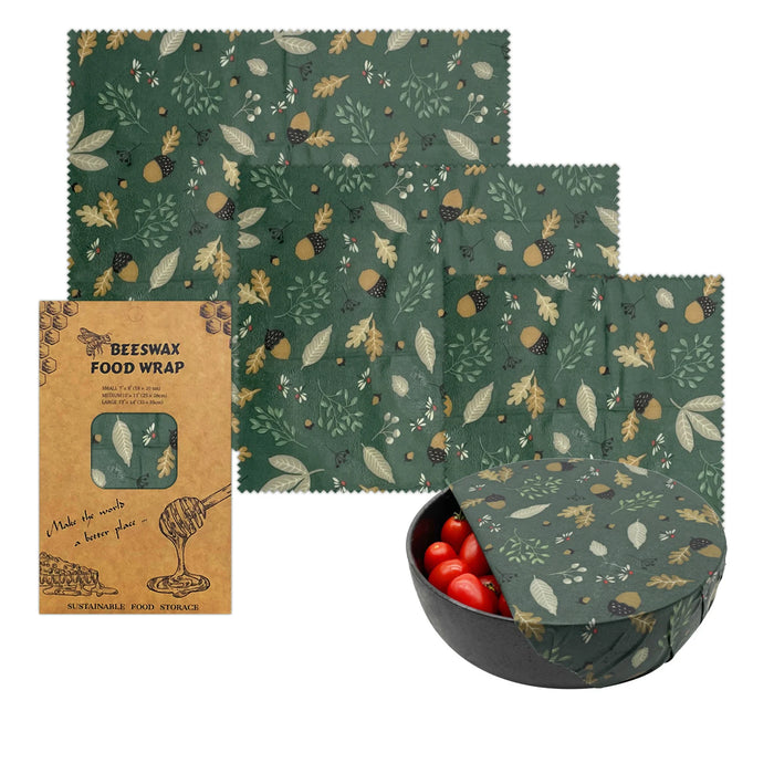Set of green patterned beeswax food wraps with a black bowl containing red fruits on a white background.