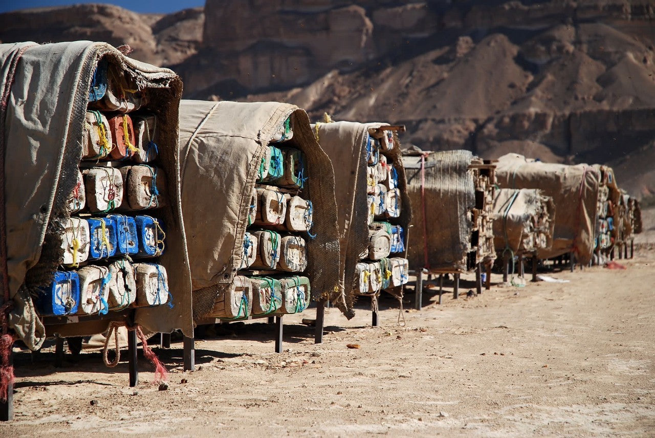 Row of covered carts with water containers in a desert setting

