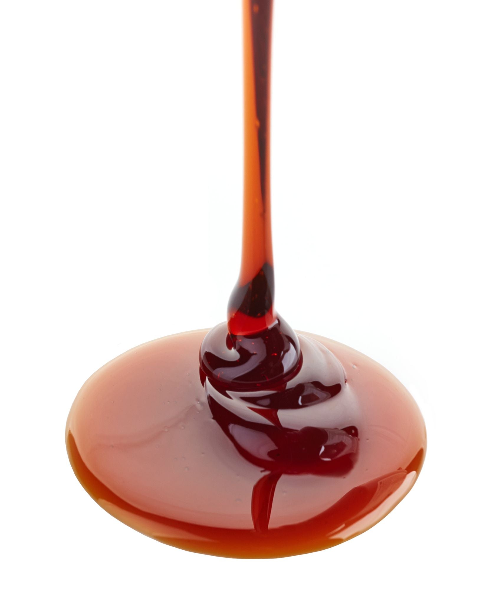 Red syrup being poured onto a white background

