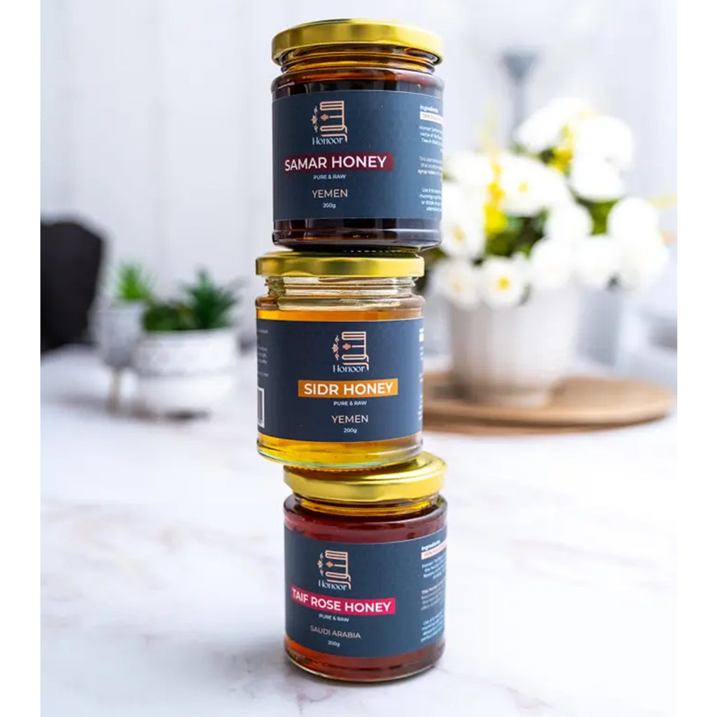 Three jars of Samar Honey stacked on a marble surface with a blurred indoor background.

