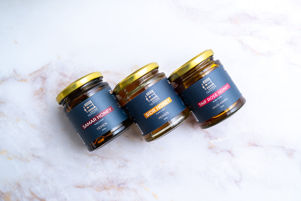 Three jars of honey with labels on a marble surface

