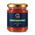 A 200g glass jar of Honoor Omani Luban Honey, featuring a dark blue label with a green banner and a metallic gold lid, set against a plain white background.

