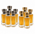 Eight perfume bottles filled with amber liquid, arranged in two rows on a white background. Each bottle has a clear faceted glass body, a hexagonal base, and an ornate metallic cap in silver and gold tones.

