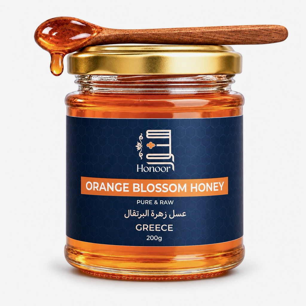 A glass jar of Honey from the brand Honoor, featuring a dark blue label and a gold metal lid. A wooden spoon filled with dripping amber honey rests on top of the jar against a clean white background.

