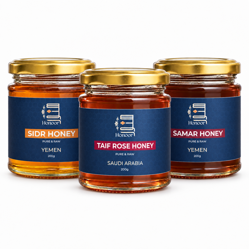 Three glass jars of honey with gold lids and blue labels are arranged on a white background. The center jar is labeled Taif Rose Honey, while the side jars are labeled Sidr Honey and Samar Honey.