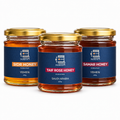 Three glass jars of honey with gold lids and blue labels are arranged on a white background. The center jar is labeled Taif Rose Honey, while the side jars are labeled Sidr Honey and Samar Honey.