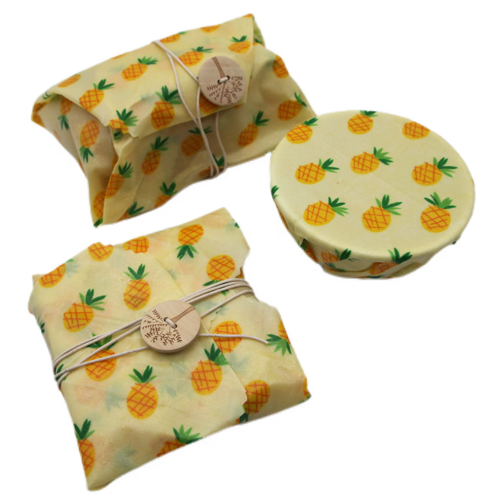 Two folded beeswax wraps with pineapple pattern on a white background

