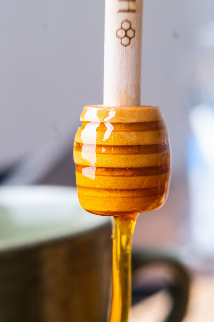 Wooden honey dipper with honey on a blurred background

