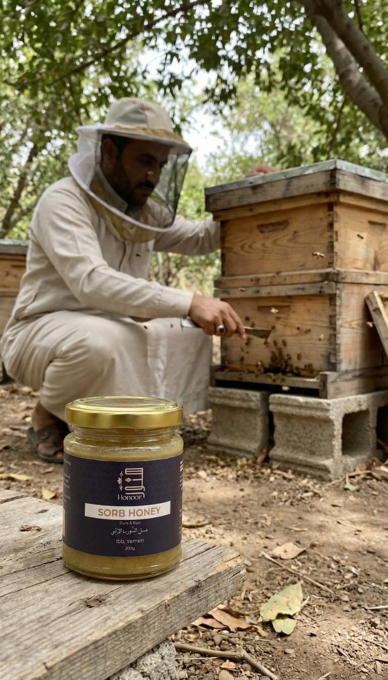 Person working with bee hives and a jar of honey on a wooden surface.

