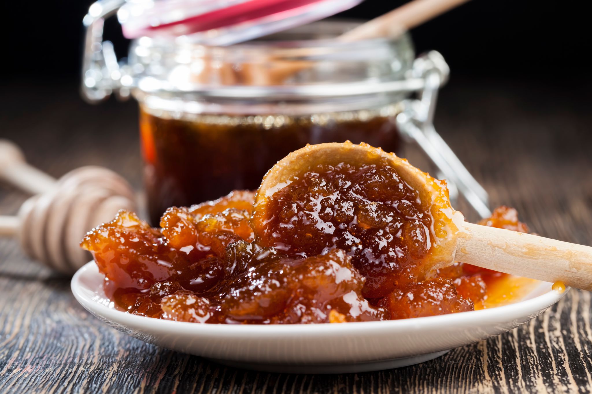 Honeycomb with honey on a wooden surface, jar of honey in the background

