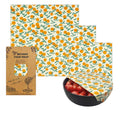 Set of beeswax food wraps with orange and green pattern on a white background

